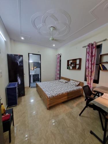 a bedroom with a bed and a table and a ceiling at HOmTEL-ROOMS by Pushpanjali QLH in Dehradun