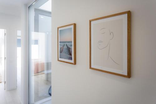 duas imagens emolduradas numa parede ao lado de uma janela em Special Cabanas em Tavira