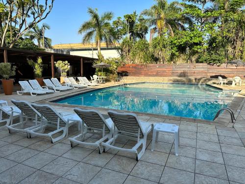 een groep stoelen en een zwembad bij Apart Hotel Delphin Guaruja in Guarujá