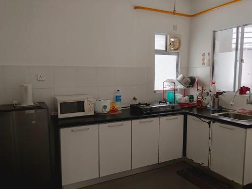 a kitchen with white cabinets and a microwave at Al Fateh Homestay Apartment in Putrajaya in Putrajaya