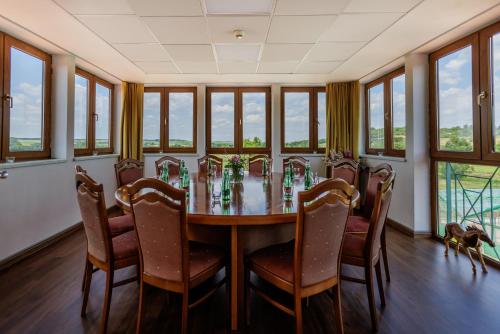 a dining room with a table and chairs and windows at Darovanský Dvůr - Wellness & Golf Hotel in Břasy