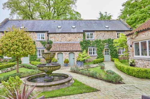 a stone house with a fountain in the yard at The Old Coach House in Ripon