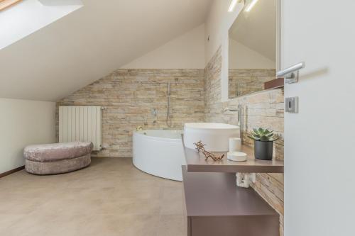 La salle de bains est pourvue d'une baignoire blanche et d'un mur en pierre. dans l'établissement Casa Mimosa, à Lierna