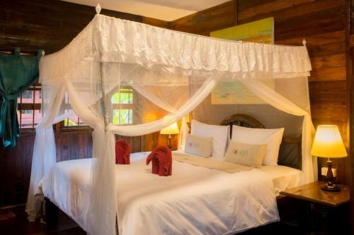 1 Schlafzimmer mit 2 Betten mit weißer Bettwäsche und einem Baldachin in der Unterkunft Country Cafe & Camping in Ban Cha-om