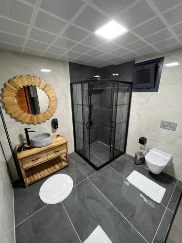 a bathroom with a shower and a toilet and a mirror at Ria süit otel bungalov in Rize