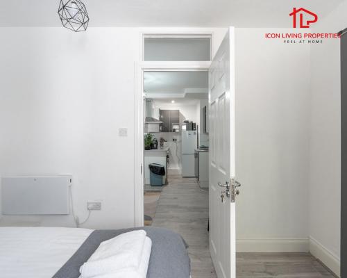a white room with a bed and a kitchen at Arch-View Apartment 1 By Icon Living Properties Short Lets & Serviced Accommodation Wembley in London