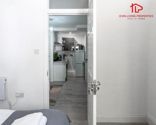 a hallway leading to a kitchen with white appliances at Arch-View Apartment 1 By Icon Living Properties Short Lets & Serviced Accommodation Wembley in London