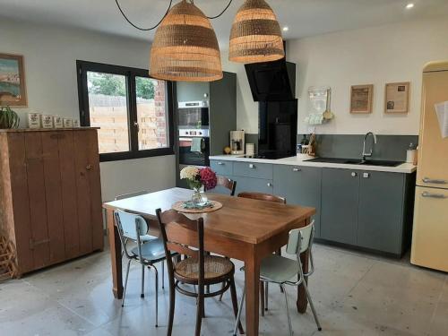 une cuisine avec une table en bois et quelques chaises dans l'établissement Le Bon Temps, pour de jolis moments, à Saint-Martin-lez-Tatinghem