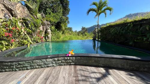a person sitting in a pool with a toy in the water at Puri Jumpungan Villas in Sidemen