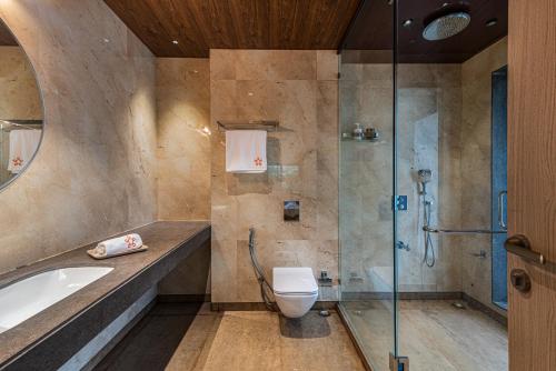 a bathroom with a tub and a toilet and a shower at SaffronStays Arcadia in Shāhāpur