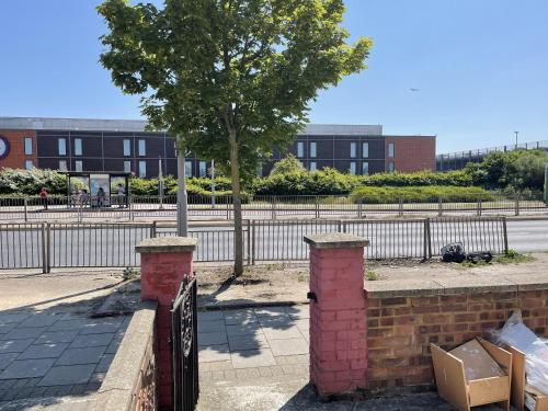 a brick fence with a tree in front of a building at Charming 2-Bed Apartment in Heathrow first floor in Hayes