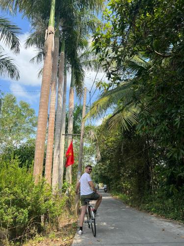 a man riding a bike down a road with palm trees at WELKOM INN in Can Tho