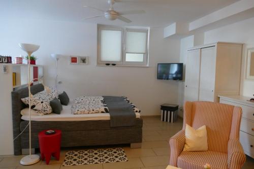 Schlafzimmer mit einem Bett, einem TV und einem Stuhl in der Unterkunft Apartment Am Markt 13 in Konz