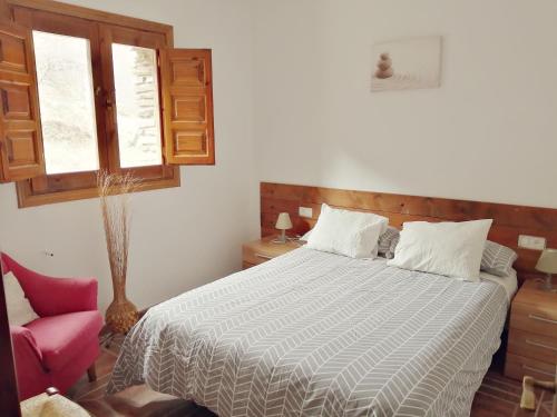 a bedroom with a bed and a pink chair at Apartamentos Balcon del Cielo in Trevélez