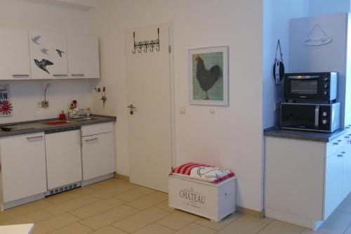 eine Küche mit weißen Schränken, einer Mikrowelle und einem Kühlschrank in der Unterkunft Apartment Am Markt 13 in Konz