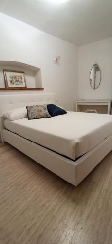 1 cama blanca grande en un dormitorio con suelo de madera en Dimora tra ciuchi e poeti, en LʼAquila