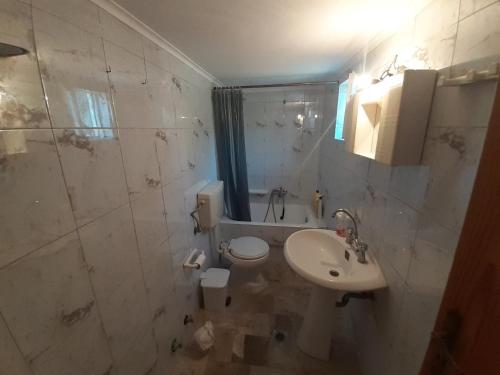 uma casa de banho branca com um lavatório e um WC em Glyfada's Family Apartment em Glyfada Fokidas