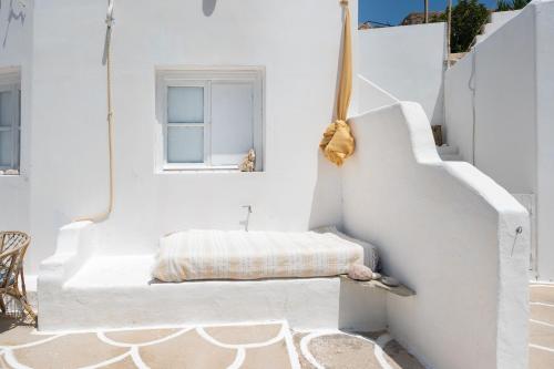 um quarto branco com um banco com uma janela em Kimolos em Sikinos