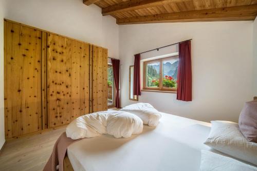 a bedroom with a bed with white sheets and a window at Ferienhaus Larch Soge Apt Helmuth in Racines