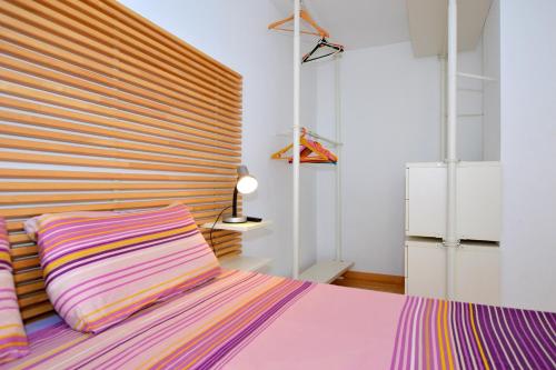 Un dormitorio con una cama morada y un gran cabecero de madera. en Coqueto apartamento a pocos metros de playa en Can Pastilla