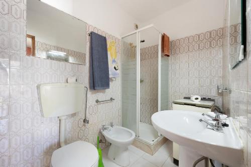 a white bathroom with a toilet and a sink at Casa do Chico in Lagoa