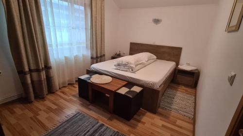 a small bedroom with a bed and a table at Hanul Ancutei in Curtea de Argeş