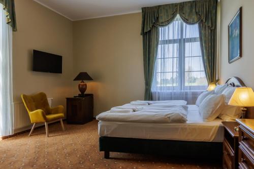 a bedroom with a bed and a window and a chair at Darovanský Dvůr - Wellness & Golf Hotel in Břasy