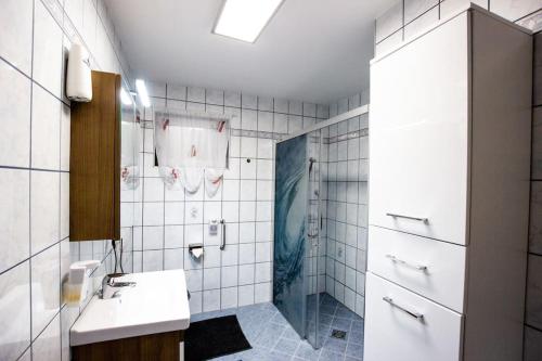 a white tiled bathroom with a sink and a shower at Ferienwohnung in Feldkirchen Dagmar und Christian! in Feldkirchen in Kärnten