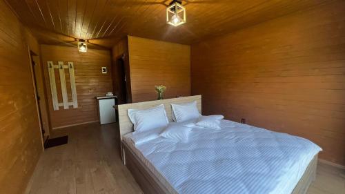 um quarto com uma cama branca e uma parede de madeira em La AMI Kaban em Câmpulung Moldovenesc