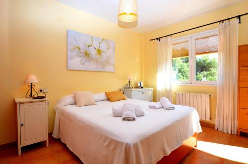 a bedroom with a bed with white sheets and a window at Bonito chalet con piscina cerca del mar in Can Pastilla