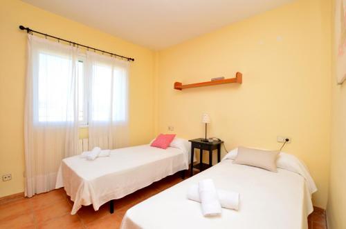 a bedroom with two beds and a window at Bonito chalet con piscina cerca del mar in Can Pastilla