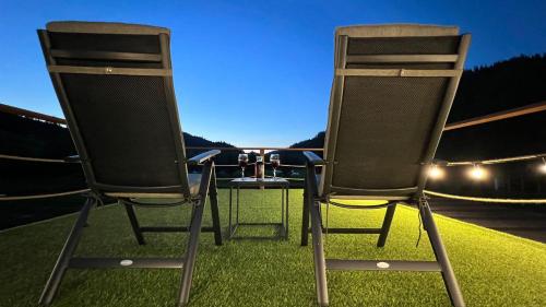 two chairs sitting on the grass in front of a car at La AMI Kaban in Câmpulung Moldovenesc
