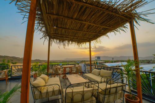 a patio with chairs and tables and a straw umbrella at Rawai Luxury Tents Pushkar in Pushkar