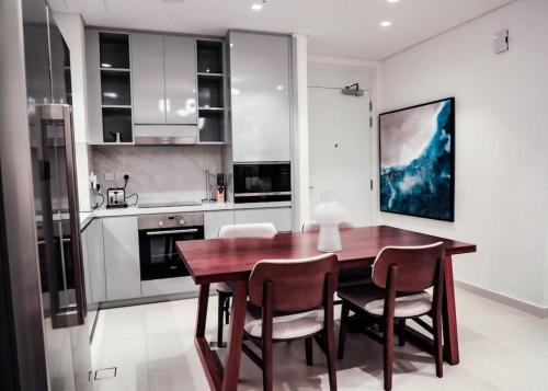 Address Resort Apartments Fujairah - 2 bedroom apartment في الفجيرة: مطبخ مع طاولة وكراسي غرفة طعام خشبية