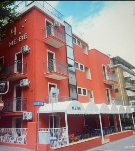 een rood gebouw met een mee bij bord erop bij HOTEL ME.BE NEW in Rimini