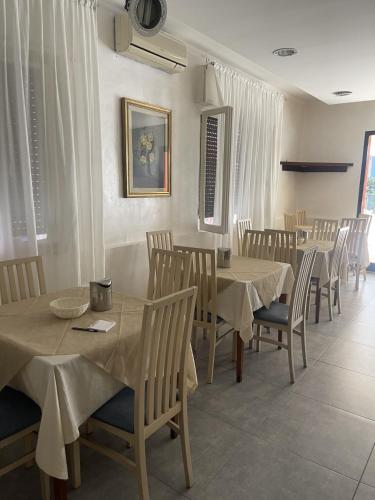 - une salle à manger avec des tables, des chaises et des rideaux blancs dans l'établissement HOTEL ME.BE NEW, à Rimini