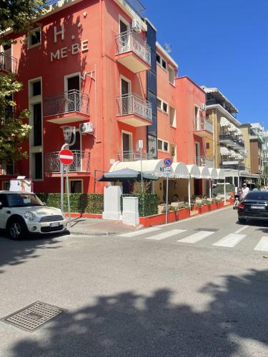 un bâtiment rouge sur le côté d'une rue de la ville dans l'établissement HOTEL ME.BE NEW, à Rimini