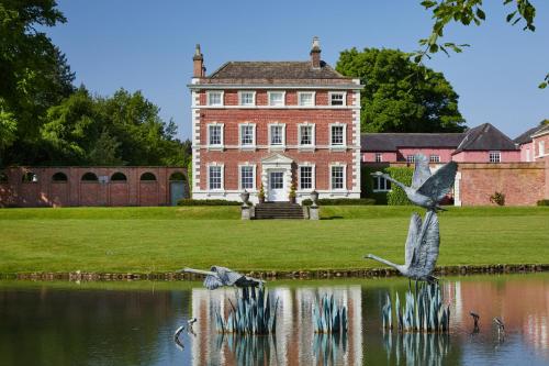 a large brick house with birds flying over a body of water at The Old Coach House in Ripon