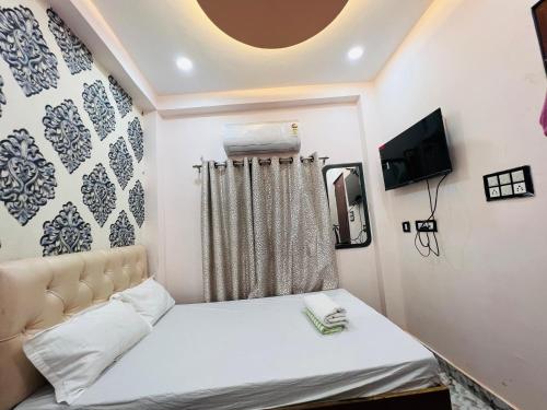 a small bedroom with a bed and a tv at The Bella Guesthouse in Varanasi