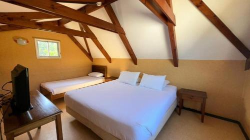 a bedroom with two beds and a television in a attic at Cabañas Huallilemu Norte - Caja Los Andes in El Quisco