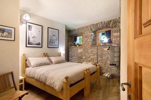 una camera con letto e parete in pietra di Chalet 1175 - Grand-haury ad Arvier