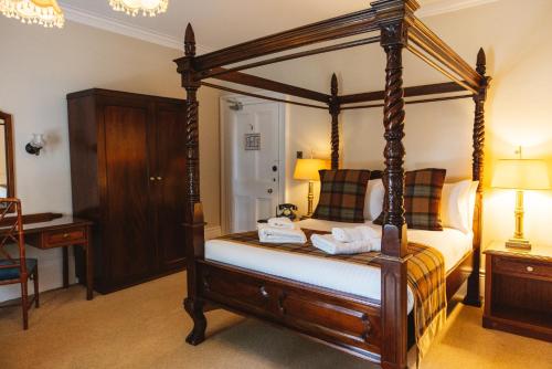 a bedroom with a canopy bed and a desk at Greshornish House Hotel in Edinbane