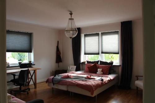 a bedroom with a bed and a desk and windows at CosyPlace; close to beach, nature, train, grocery in Köpingebro