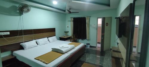 a bedroom with a large bed with a fan on it at Sri Murugan Beach Paradise Hotel in Mahabalipuram