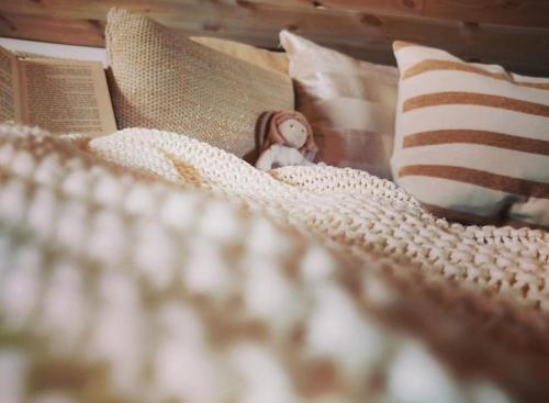 una muñeca sentada sobre una cama con un libro en CosyPlace; close to beach, nature, train, grocery, en Köpingebro