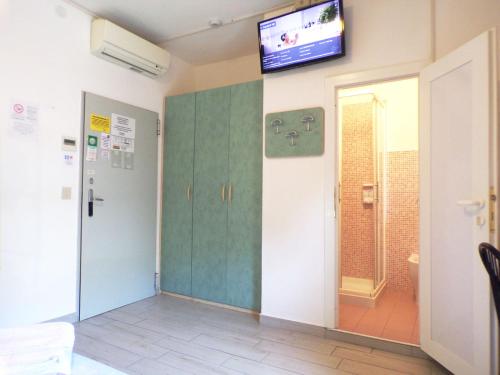 ミラノ・マリッティマにあるHotel Esedraの壁にテレビとドアが備わる部屋