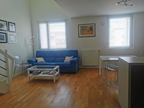 een woonkamer met een blauwe bank en een tafel bij Duplex lumineux Saint Ouen sur Seine in Saint-Ouen
