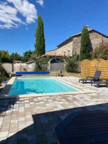 une piscine avec deux chaises à côté d'une maison dans l'établissement Petite villa avec piscine privative, à Aigremont