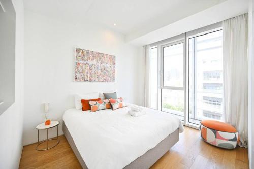 a white bedroom with a large bed and a window at Exclusive 2BR Meier Tower W/Parking - Rothschild in Tel Aviv