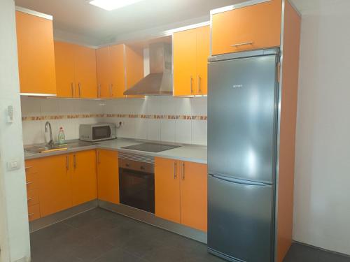a kitchen with orange cabinets and a stainless steel refrigerator at Jaral Home in Puerto de Santiago